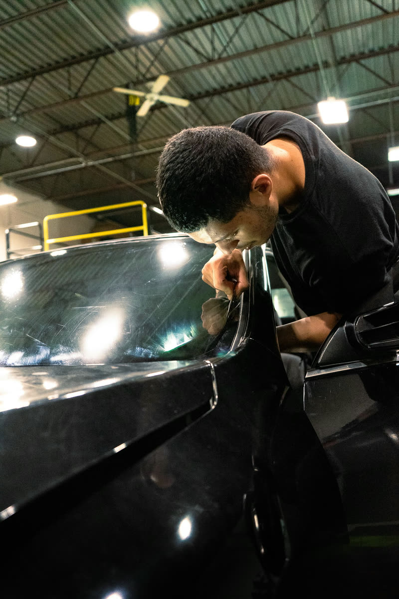 A technician working on a black car in the shop